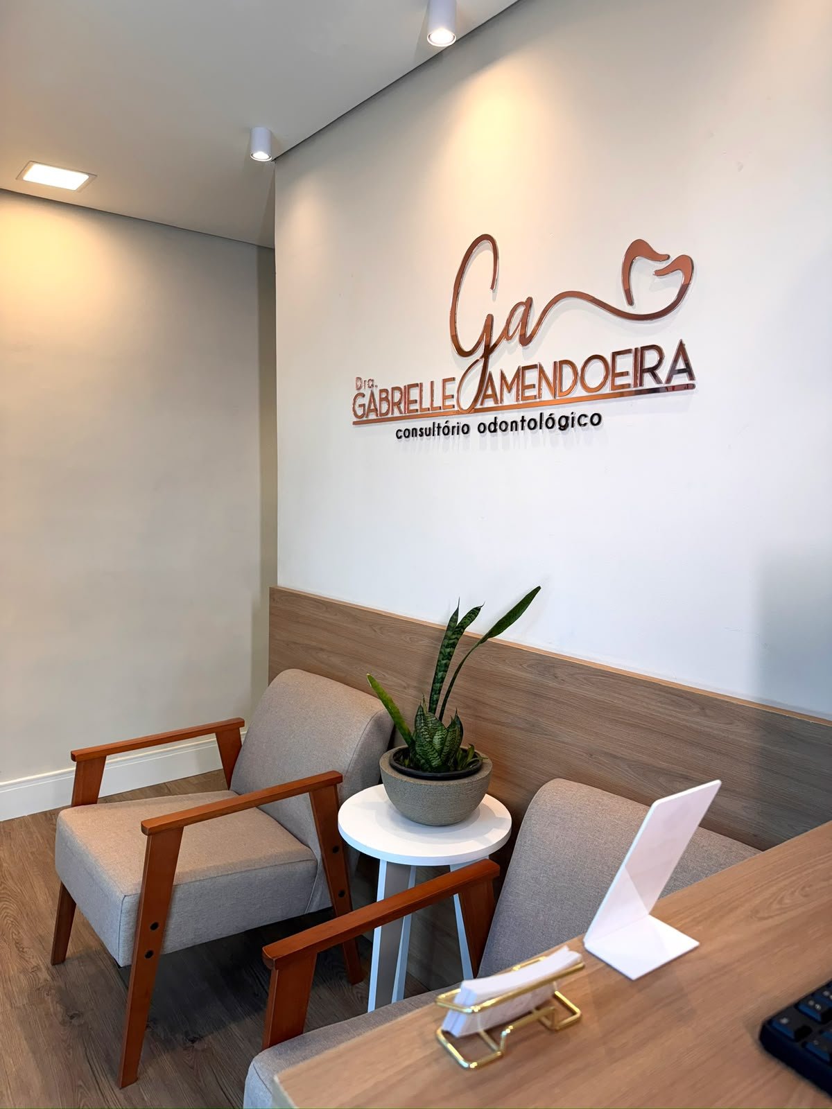 Detalhe da recepção do consultório, com poltrona em linho e luz natural